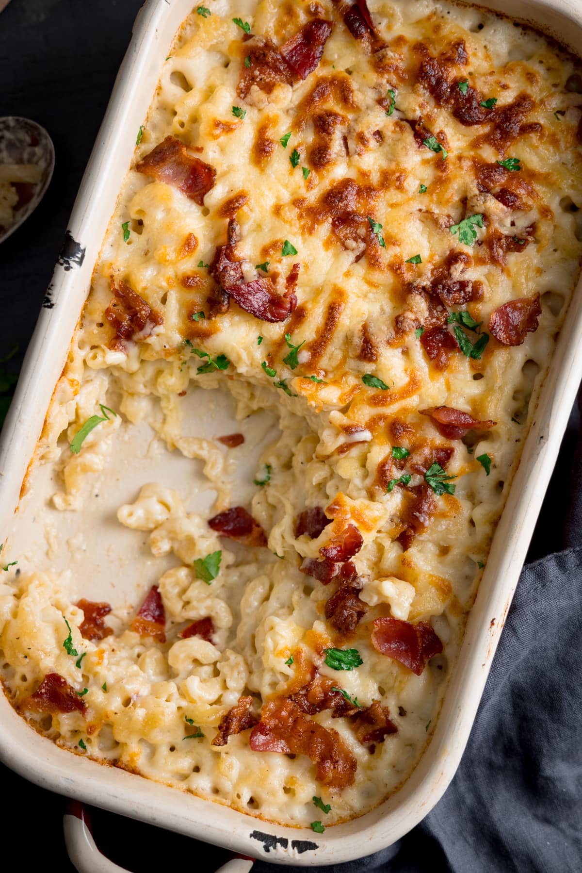 close up picture of a baking dish full of mac n cheese with a scoop full taken out.