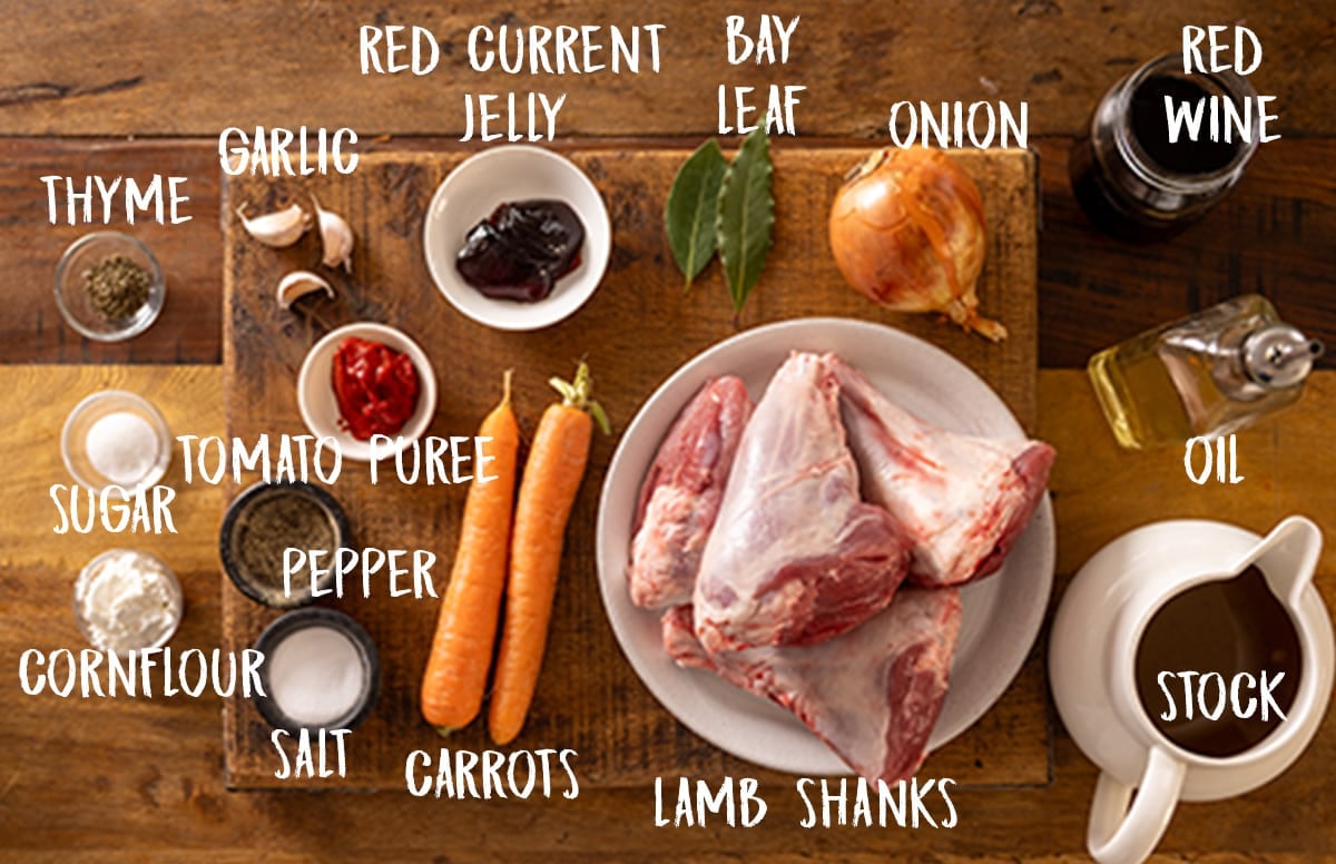 Ingredients for slow cooker lamb shanks on a wooden board. There is a white text overlay for the name of each ingredient.