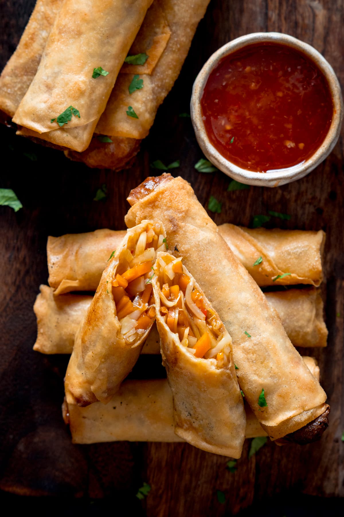 Close up picture of a sliced open vegetable spring roll showing the filling. The open spring roll is sat on top of a stack of other spring rolls.