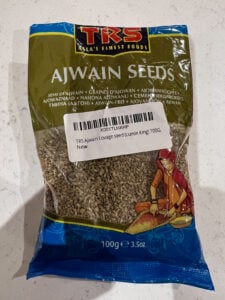 Packet of ajwain seeds on a white surface.