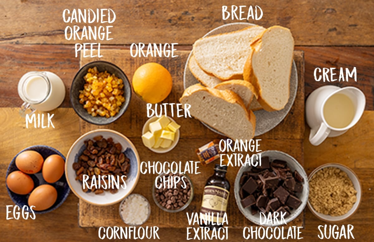 Ingredients for chocolate orange bread and butter pudding on a wooden board.