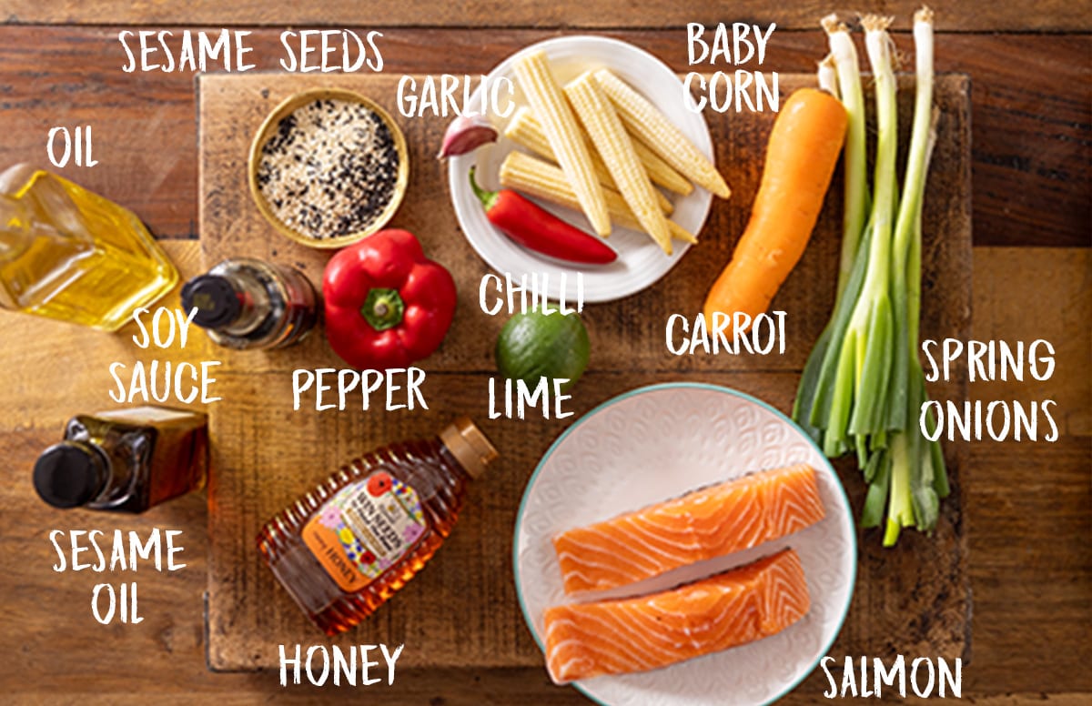 Overhead photo of labelled salmon en papillote ingredients on a wooden board.