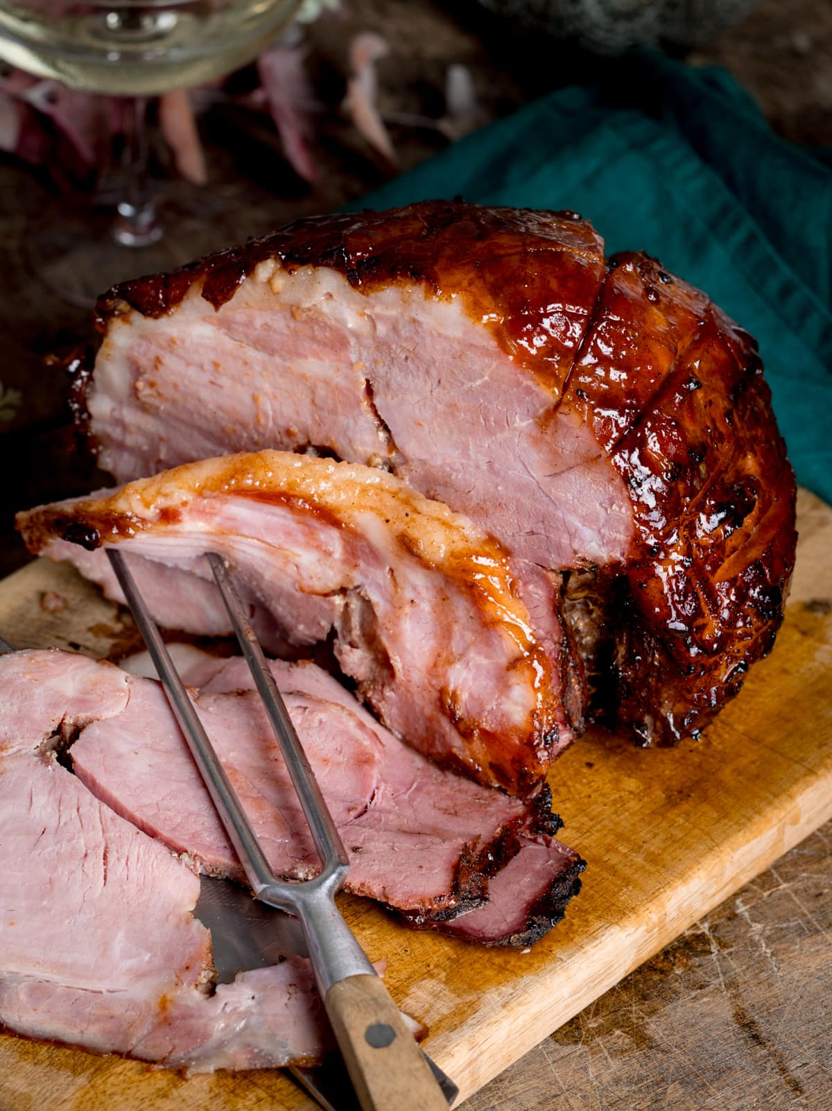 A slow cooker gammon joint with some slices sliced off and carving fork in the foreground.