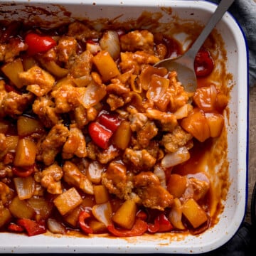 Over head photo of a white enamel baking dish full of baked sweet and sour chicken.