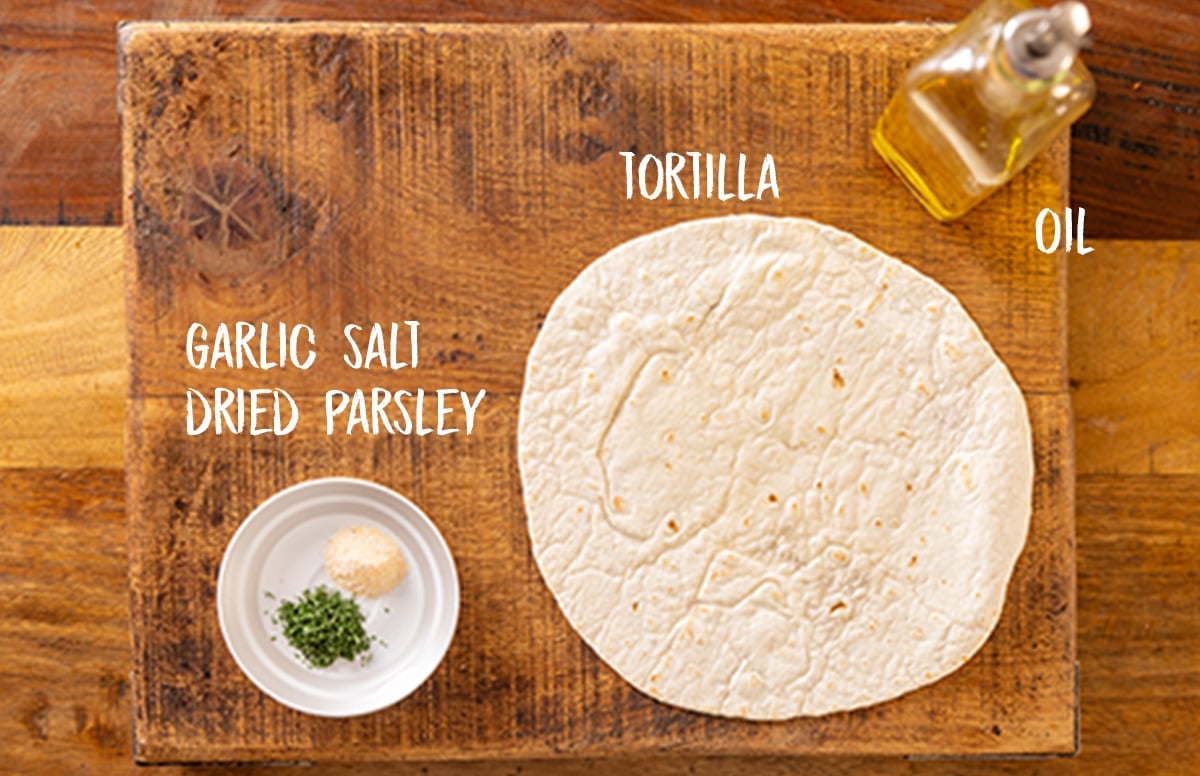 Ingredients for homemade crispy tortilla strips on a wooden board.