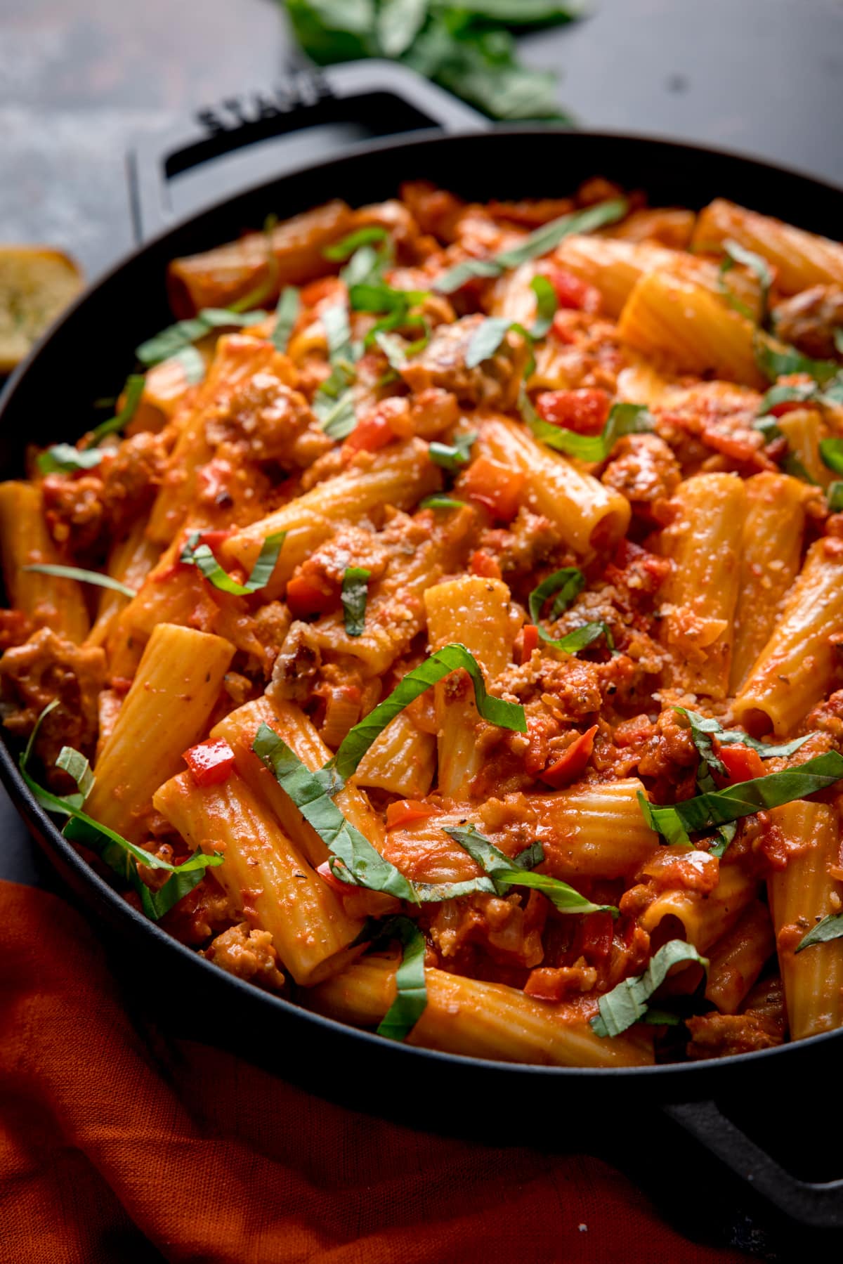 Close up photo of spicy sausage pasta in a black skillet.