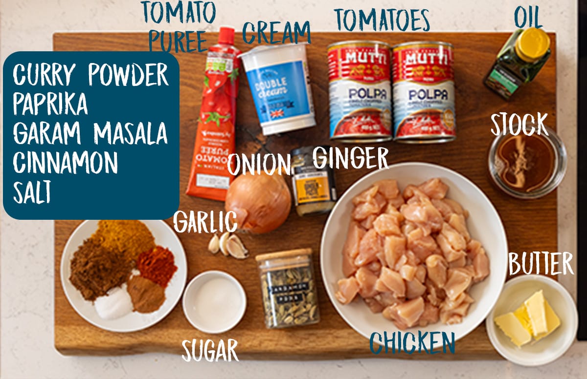 Ingredients for crock pot butter chicken on a large wooden chopping board.