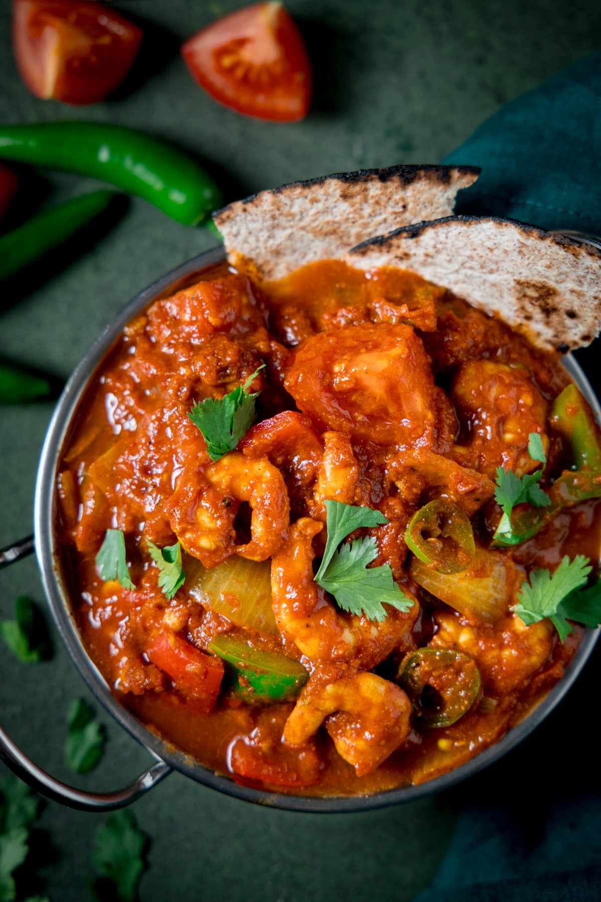 Close up picture of a prawn balti in a balti dish on a green background.