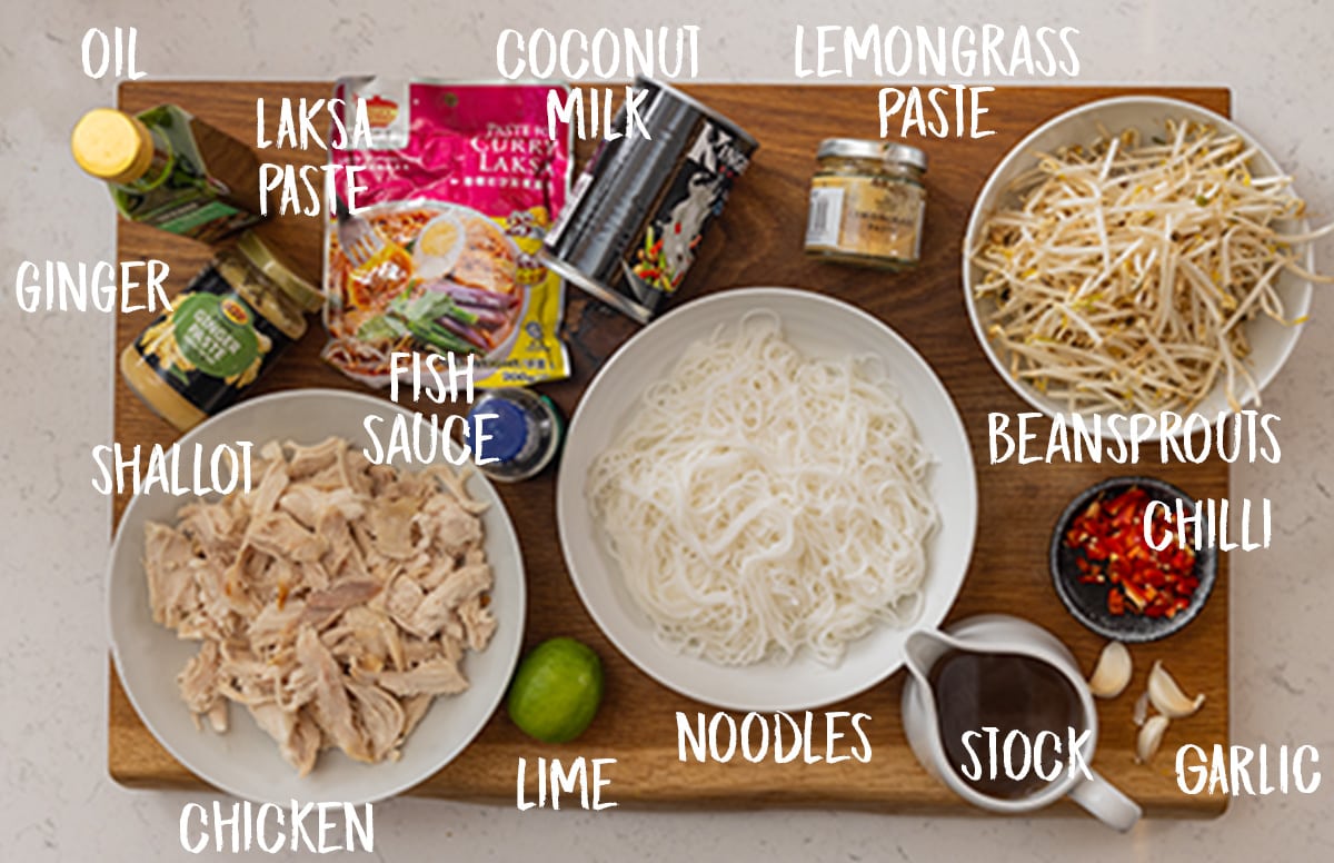 Ingredients for quick chicken laksa on a wooden chopping board.