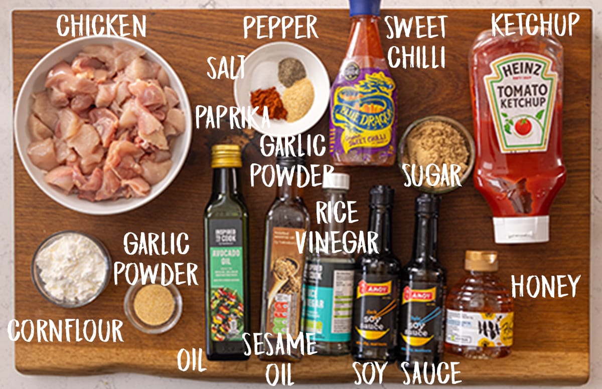 Ingredients for air fryer sesame chicken on a wooden board. The ingredients are labelled in white text.