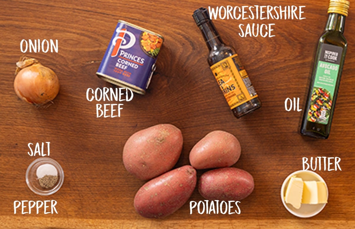 Ingredients for corned beef hash on a wooden board. The ingredients are labelled.