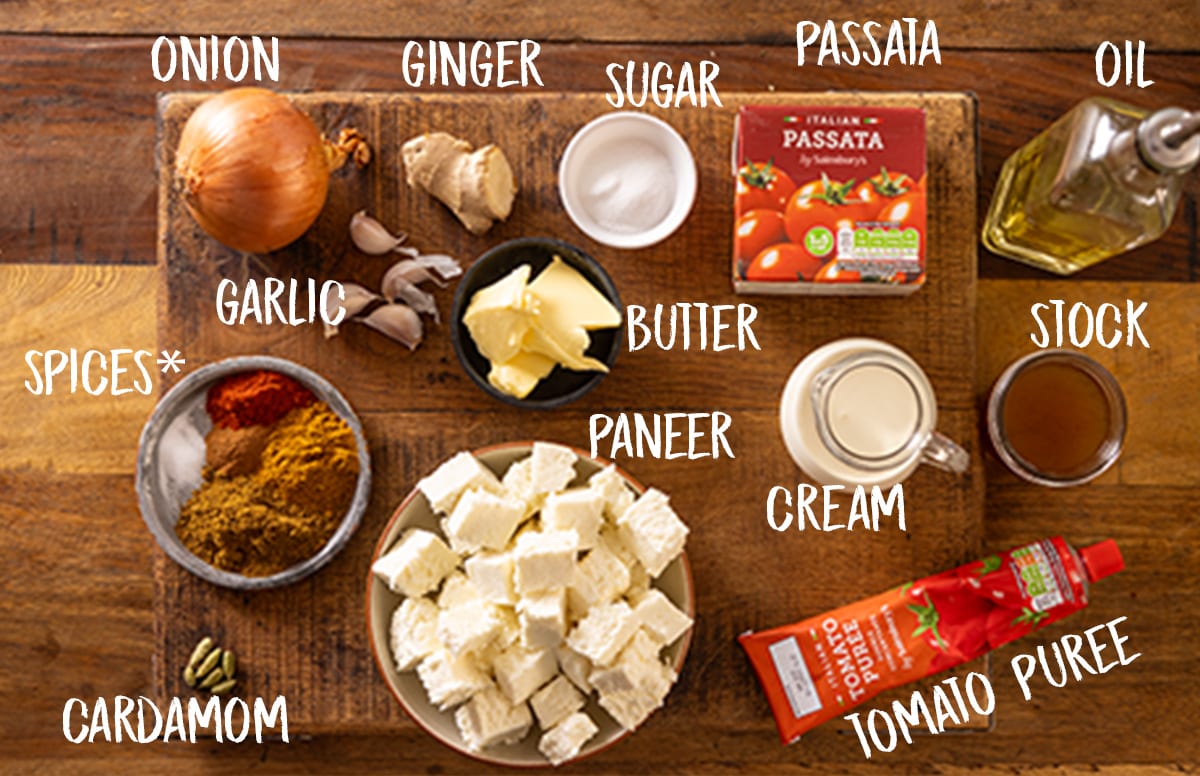 Labelled ingredients for making a paneer curry on a wooden board.
