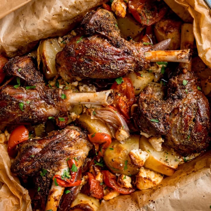 Greek lamb kleftiko, featuring roasted lamb shanks with potatoes, tomatoes, and herbs all perfectly wrapped in baking paper.