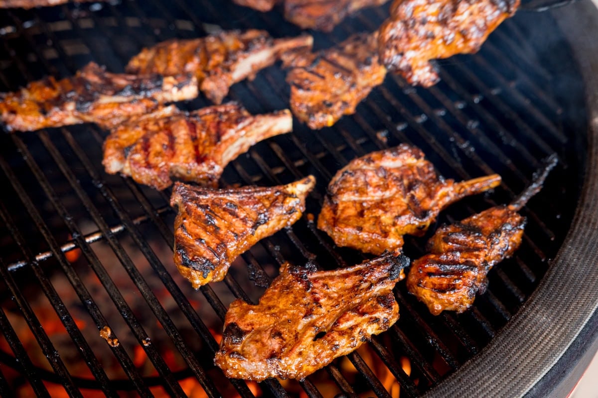 Lamb chops cooking on a  bbq grill with hot coals underneath.