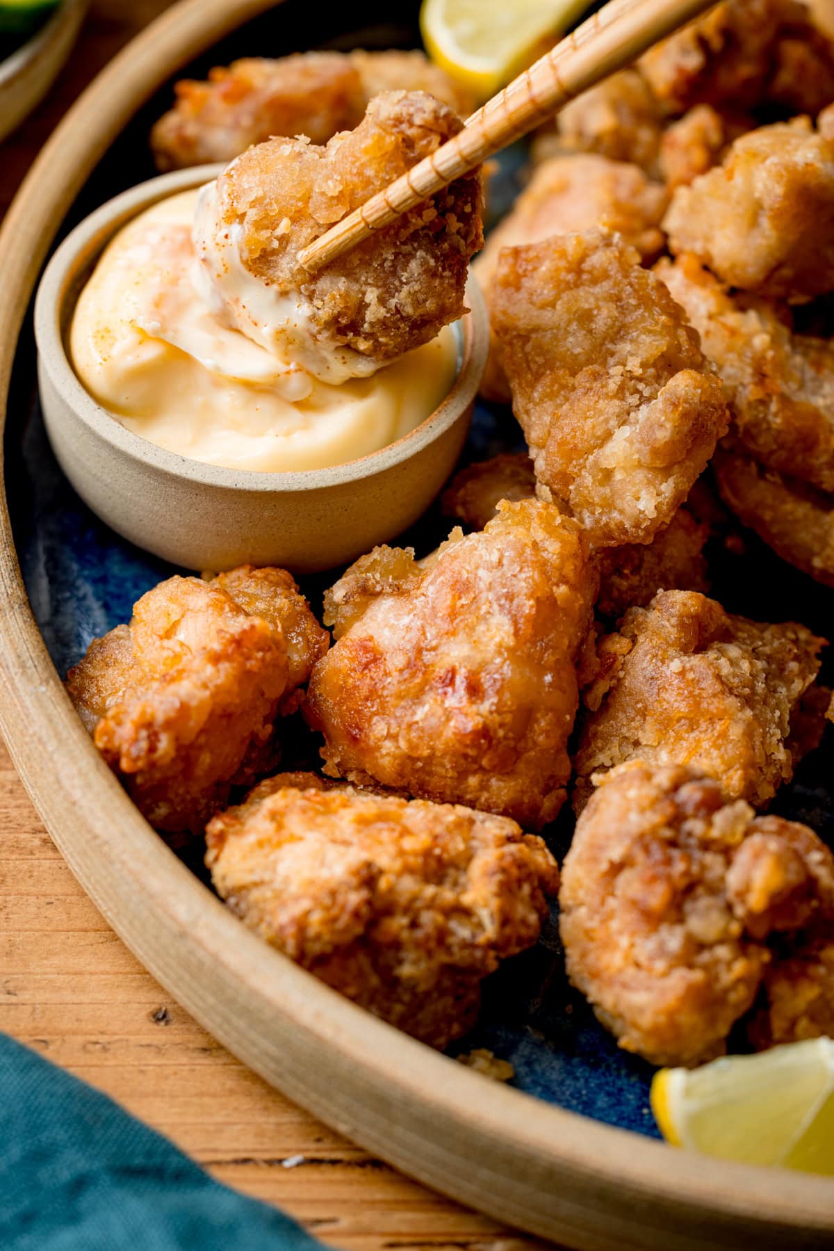 A close-up of Air Fryer Chicken Karaage pieces on a plate, with one piece being dipped into kewpie mayonnaise using chopsticks.