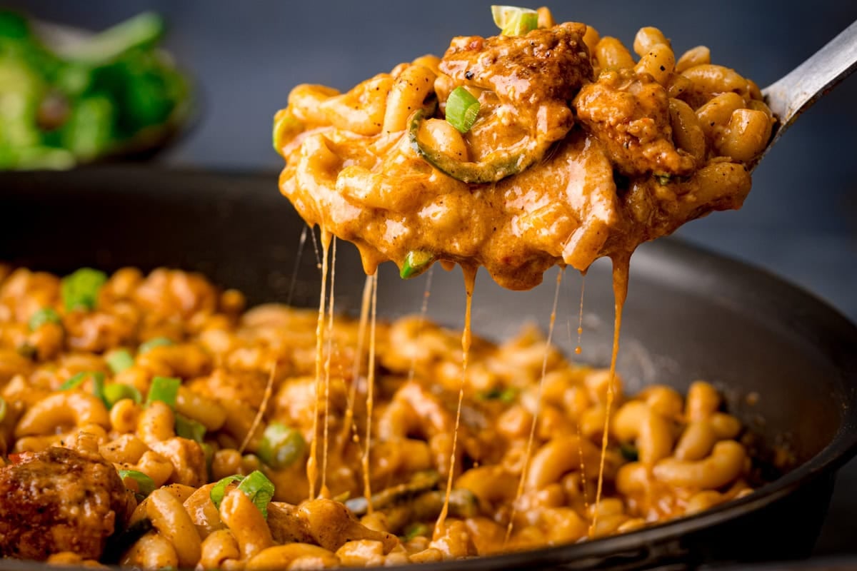 A spoonful of spicy, cheesy pasta lifted from a pan, showing the cheese pull.