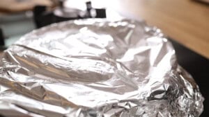 A close-up of a one pan chicken pasta covered with aluminium foil.