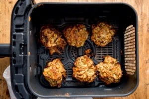 Six Onion Bhaji fritters in the basket of an air fryer.