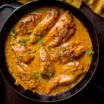 Creamy honey mustard chicken topped with chopped parsley in a black frying pan.