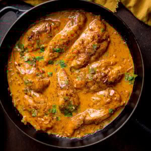 Creamy honey mustard chicken topped with chopped parsley in a black frying pan.
