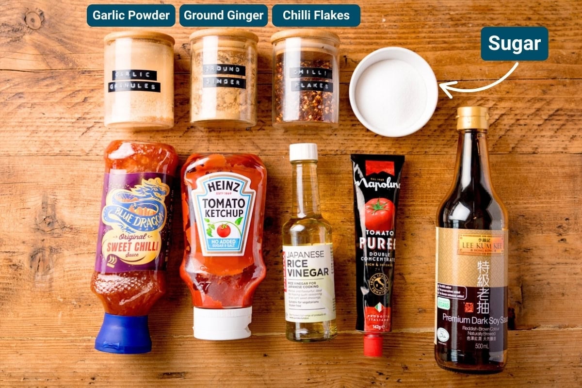 Ingredients for crispy chilli beef sauce on a wooden table including: tomato purée, sweet chilli sauce, soy sauce and ketchup.