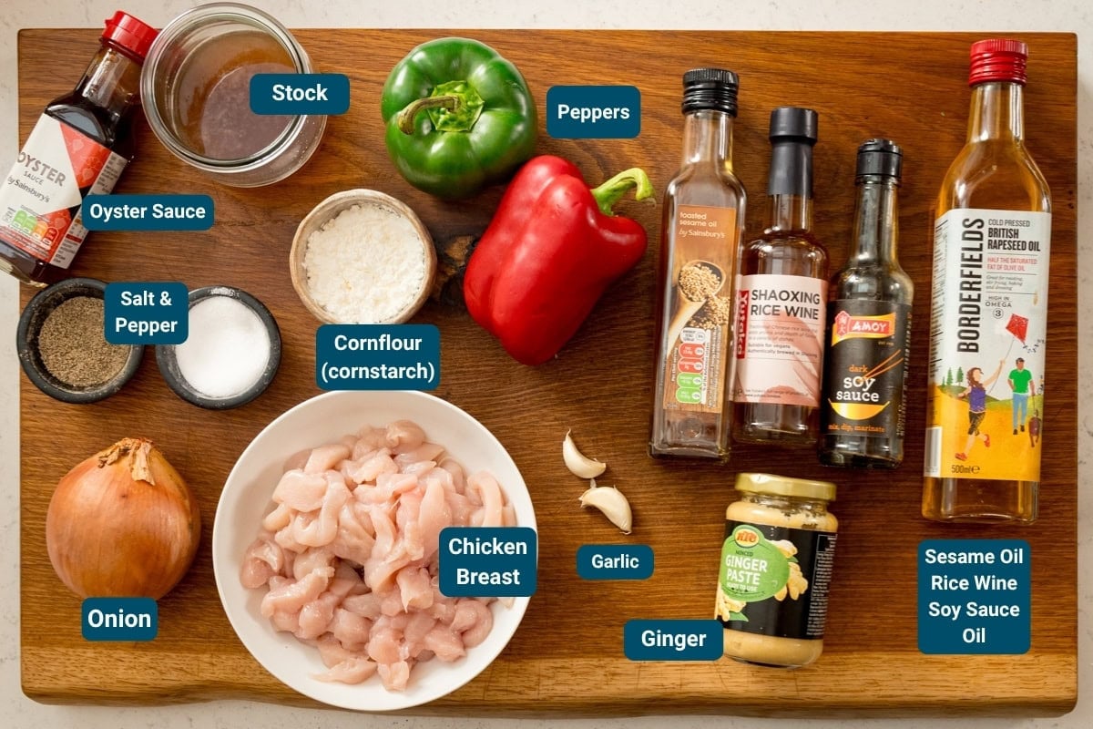 Ingredients for Chinese-style black pepper chicken on a wooden board, all clearly labelled. Including chopped chicken breast, vegetables, sauces, spices, and seasonings.