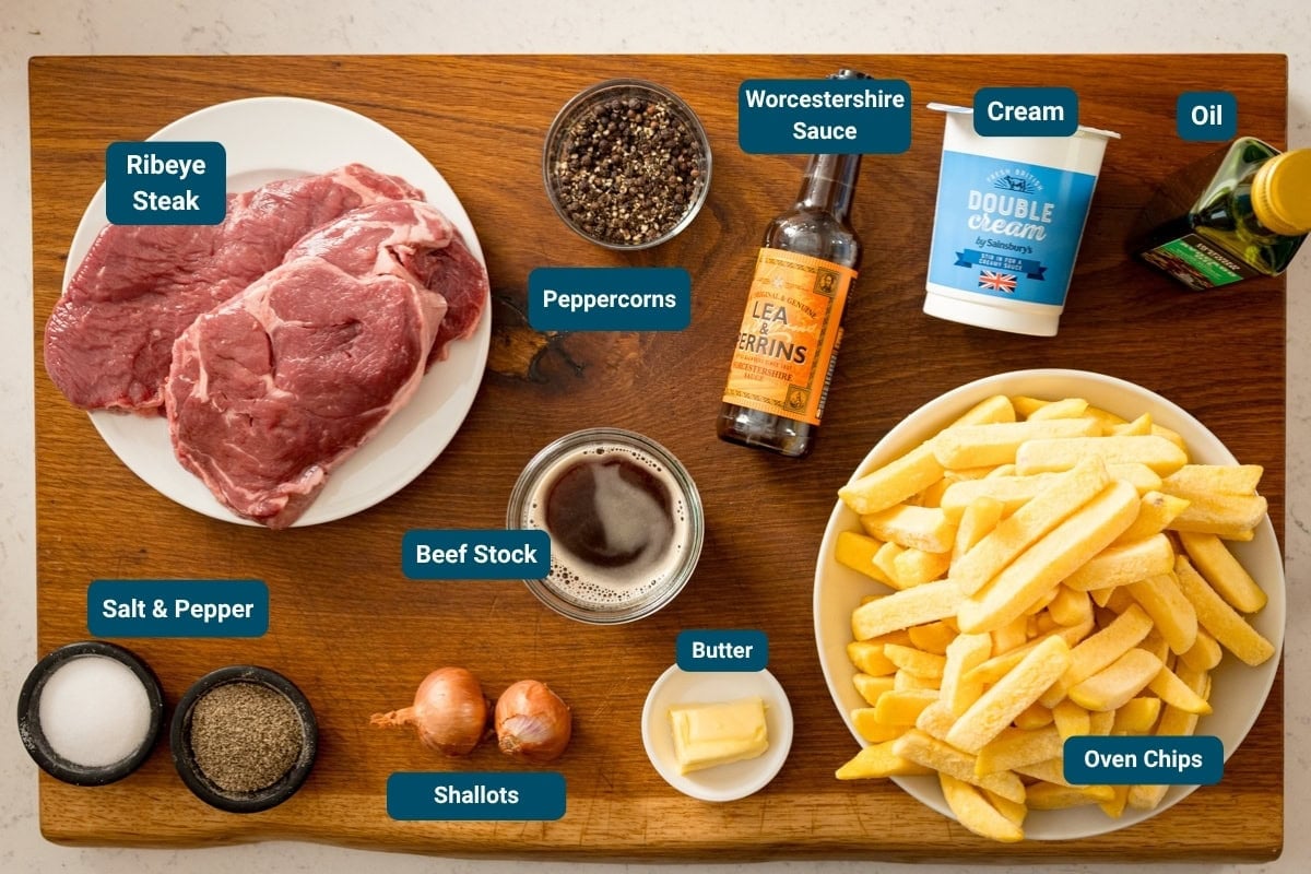A wooden board displays labelled ingredients steaky chips - ribeye steak, chips, double cream, oil, shallots, butter, Worcestershire sauce, beef stock, peppercorns, salt and pepper.