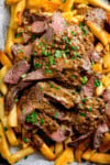 Sliced steak with rich peppercorn sauce served over chunky chips, garnished with chopped parsley.