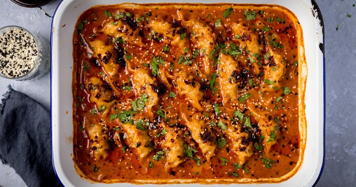 Gyoza dumplings on a tray in a red Thai curry sauce
