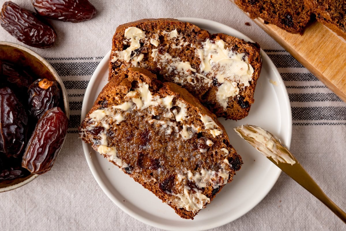 2 slices of buttered malt loaf on a white round plate.