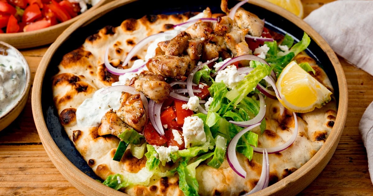 Flatbread topped with diced griddled chicken pieces, red onion slices, cubes of feta