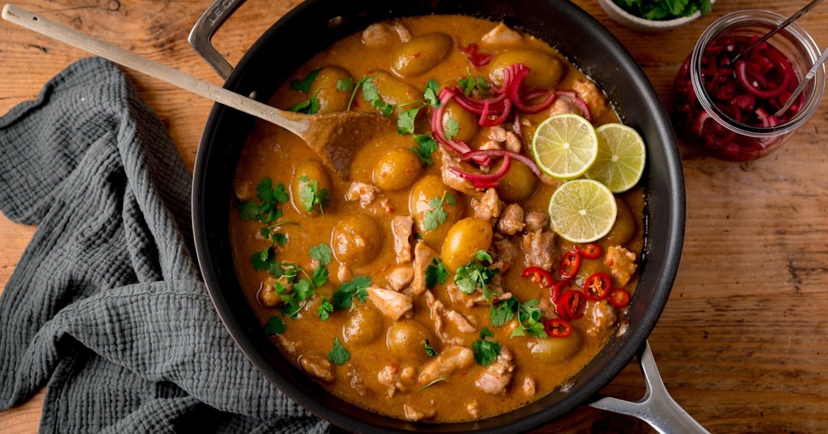 A pan with diced chicken and baby potatoes in a creamy curry sauce sprinkled with coriander.