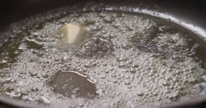 Butter melting and bubbling in a heated frying pan.