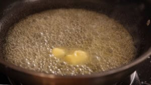 Butter melting and bubbling in a pan on a hob.
