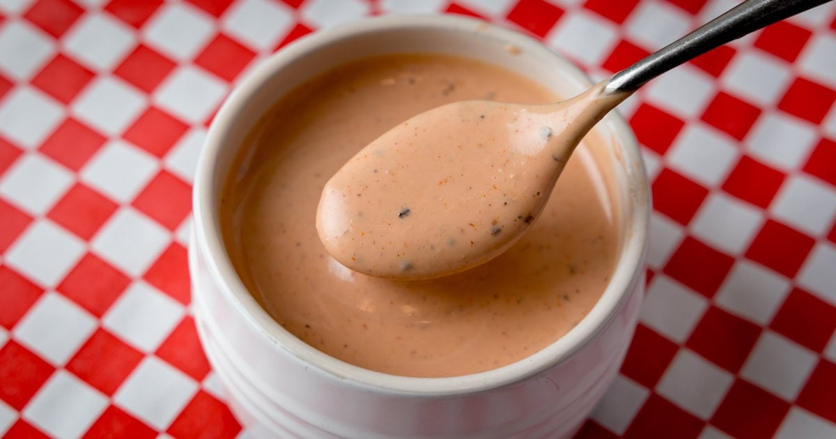A small white pot with a creamy, spicy, pink mayo sauce.