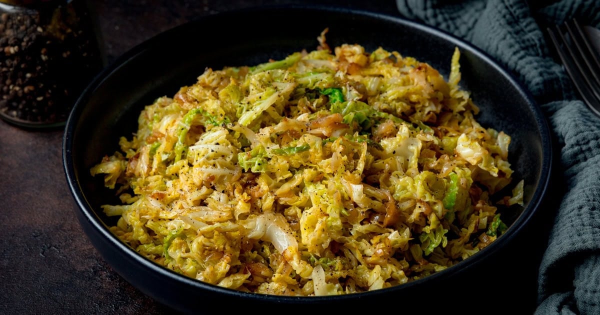 A black bowl with shredded cooked cabbage.