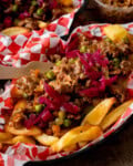 Shepherd’s pie chips topped with minced lamb, peas, and pickled red cabbage, served in a red-and-white checkered paper liner.