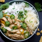 White chilli chicken in a bowl with rice, cheese, jalapenos and spring onions